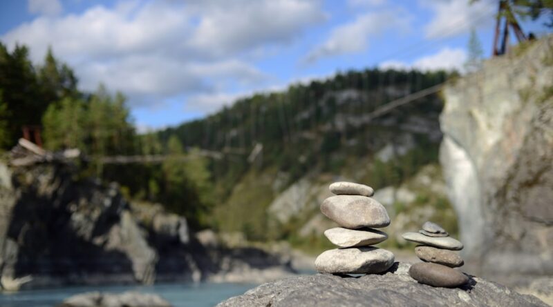 a pile of rocks sitting on top of a rock next to a river