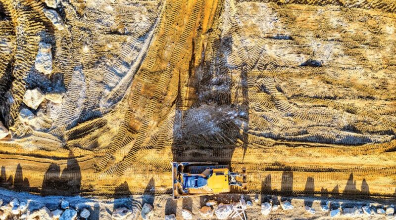 Aerial shot of construction site in Rochester, MN, featuring an excavator on dirt road.