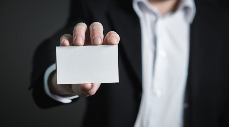 A man in a suit presenting a blank business card for corporate usage.