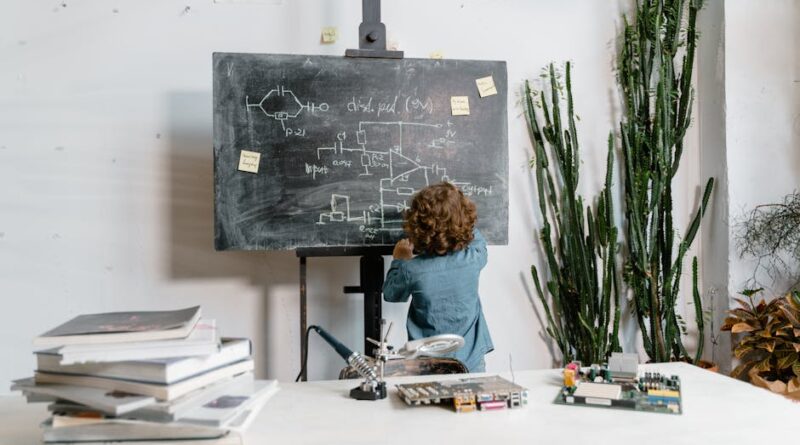 Curious young boy drawing STEM concepts on a blackboard indoors, surrounded by educational materials.